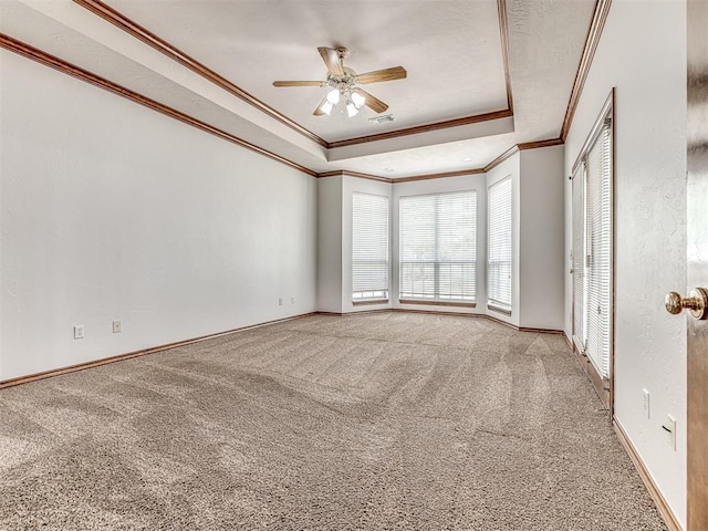 carpeted empty room featuring ceiling fan, ornamental molding, and a tray ceiling