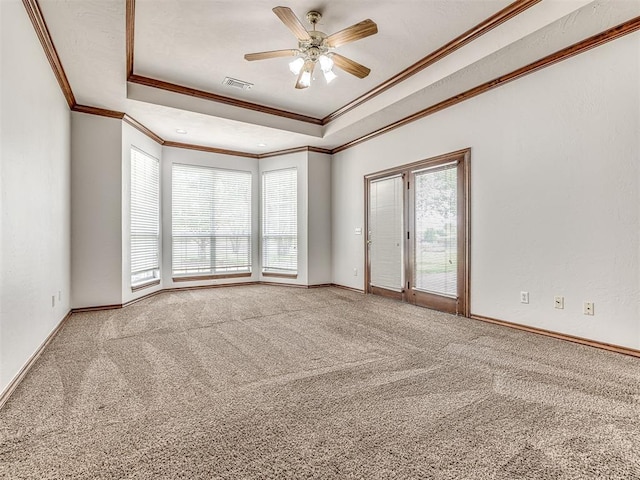 carpeted spare room featuring a tray ceiling, ceiling fan, and crown molding