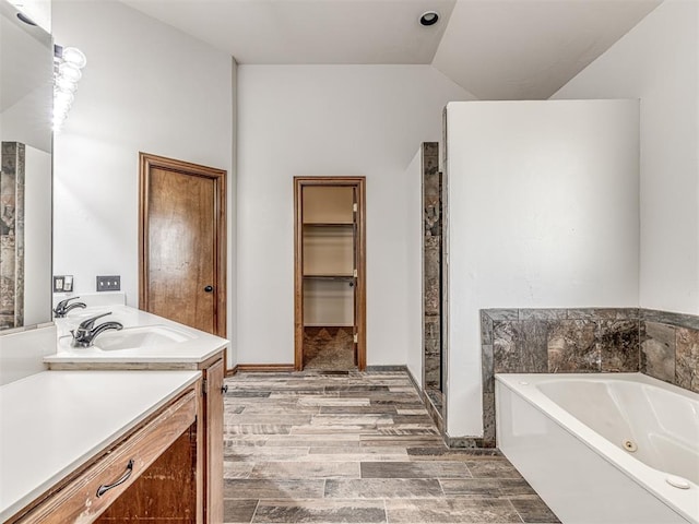 bathroom featuring a bath, vanity, wood-type flooring, and vaulted ceiling