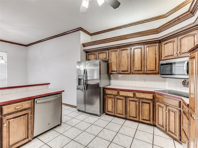 kitchen featuring ceiling fan, decorative backsplash, ornamental molding, tile counters, and stainless steel appliances