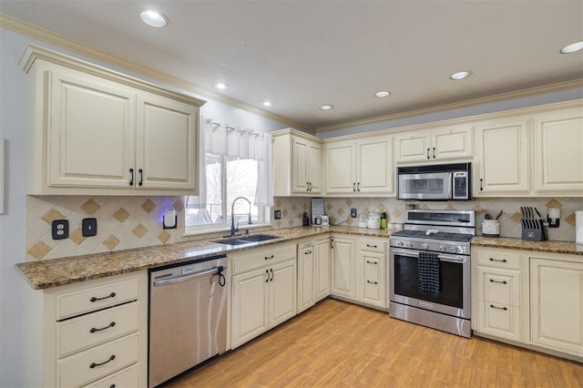 kitchen featuring ornamental molding, sink, appliances with stainless steel finishes, and cream cabinets