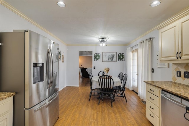 kitchen featuring cream cabinetry, appliances with stainless steel finishes, light hardwood / wood-style flooring, and ornamental molding