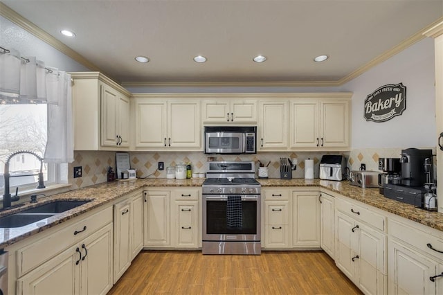 kitchen featuring cream cabinets, sink, ornamental molding, and appliances with stainless steel finishes