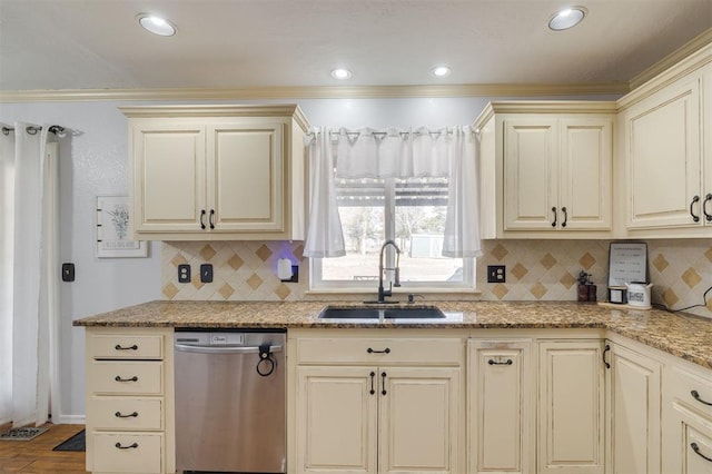 kitchen with light stone counters, dishwasher, cream cabinetry, and sink