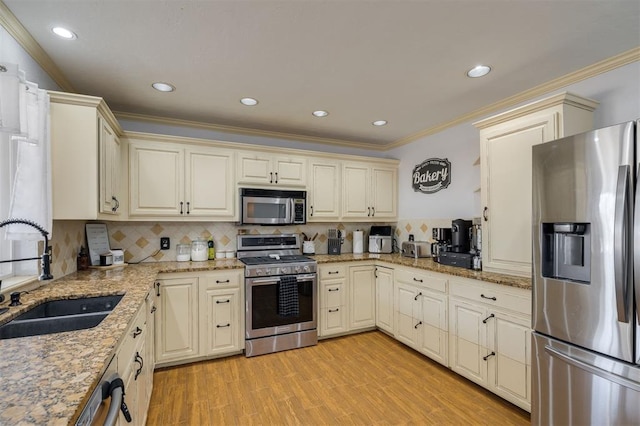 kitchen with light stone countertops, appliances with stainless steel finishes, light wood-type flooring, crown molding, and sink