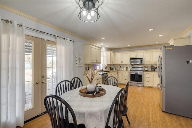 dining room featuring light hardwood / wood-style floors, ornamental molding, sink, and french doors