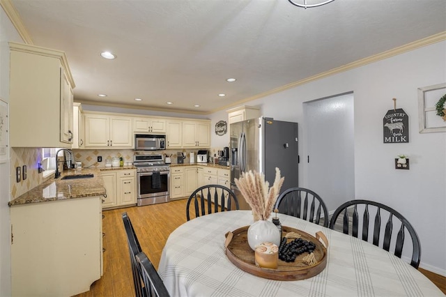 dining space featuring sink, ornamental molding, and light hardwood / wood-style flooring