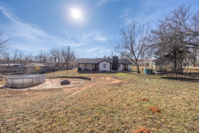 view of yard featuring an outdoor fire pit and a trampoline