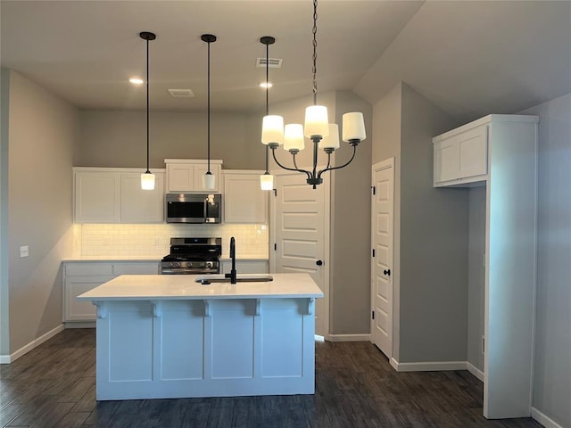 kitchen featuring pendant lighting, stainless steel appliances, a kitchen island with sink, and dark wood-type flooring