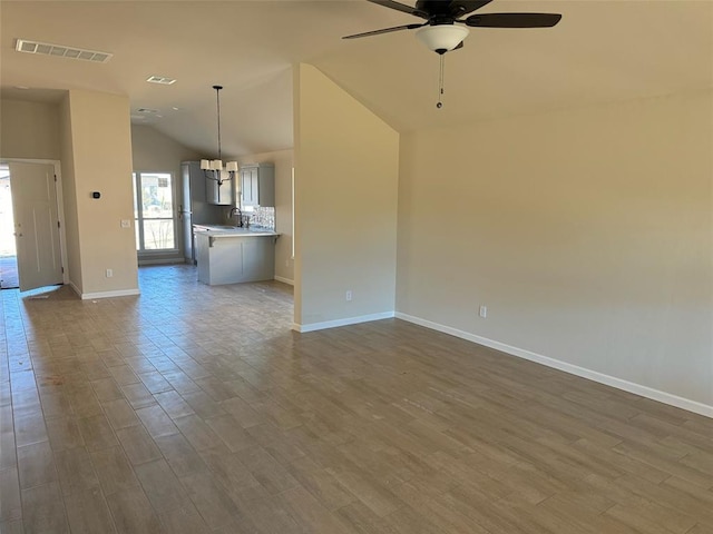 unfurnished living room with hardwood / wood-style flooring, vaulted ceiling, ceiling fan, and sink