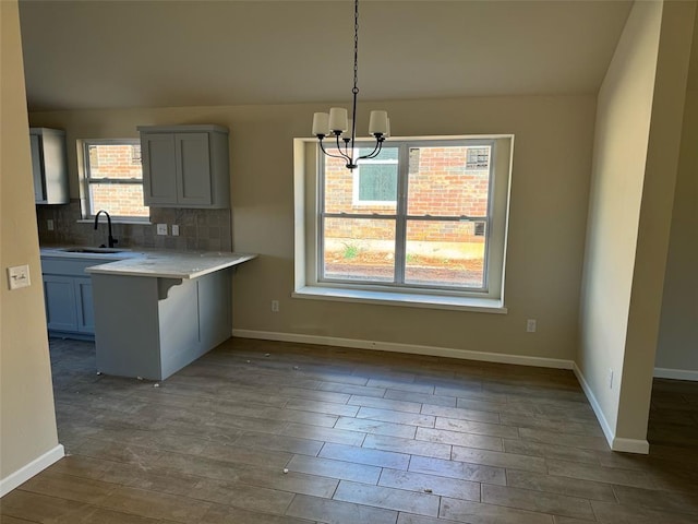 kitchen featuring sink, a kitchen breakfast bar, a notable chandelier, kitchen peninsula, and decorative light fixtures