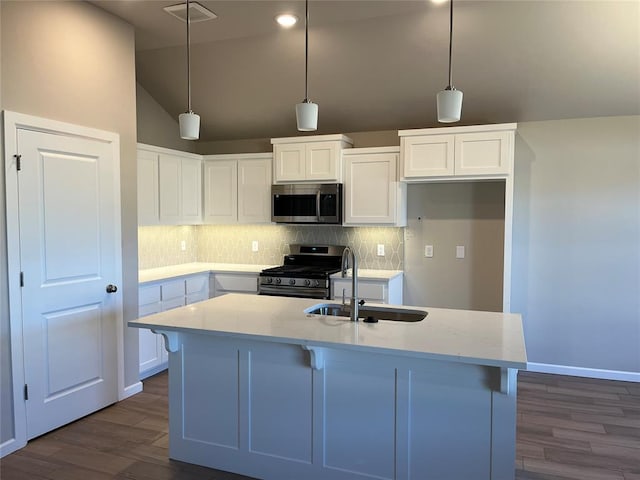 kitchen with a sink, white cabinets, appliances with stainless steel finishes, backsplash, and dark wood-style floors