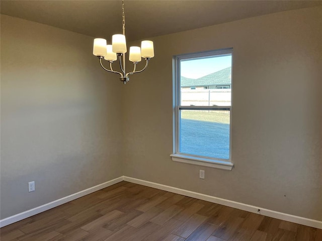 empty room with baseboards, dark wood finished floors, and an inviting chandelier