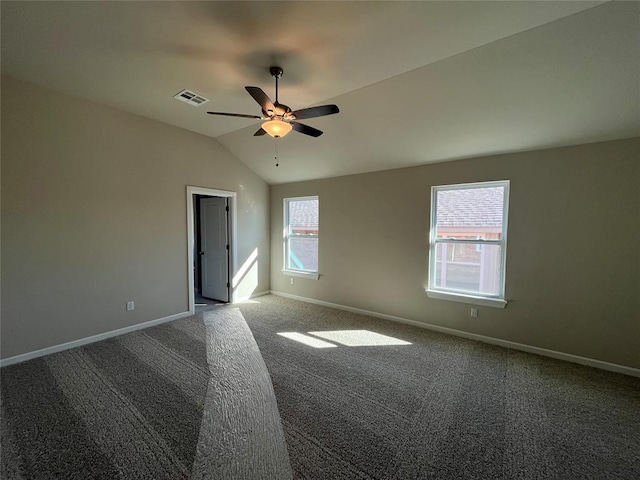 empty room featuring lofted ceiling, visible vents, and baseboards