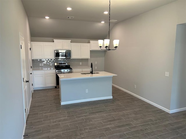 kitchen featuring dark wood-type flooring, hanging light fixtures, sink, appliances with stainless steel finishes, and white cabinetry