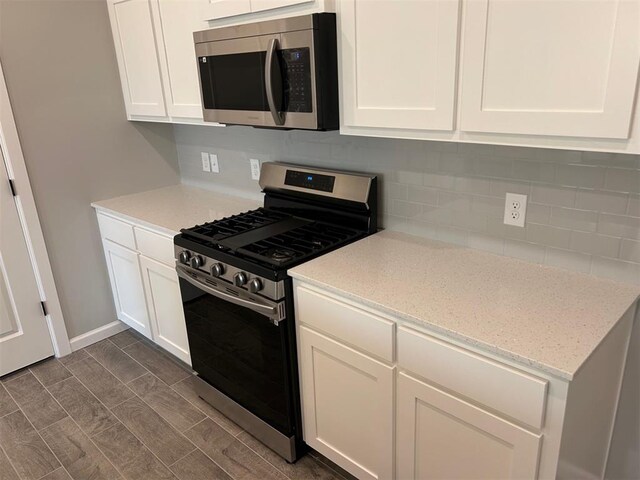 kitchen featuring white cabinetry, stainless steel appliances, and dark wood-type flooring