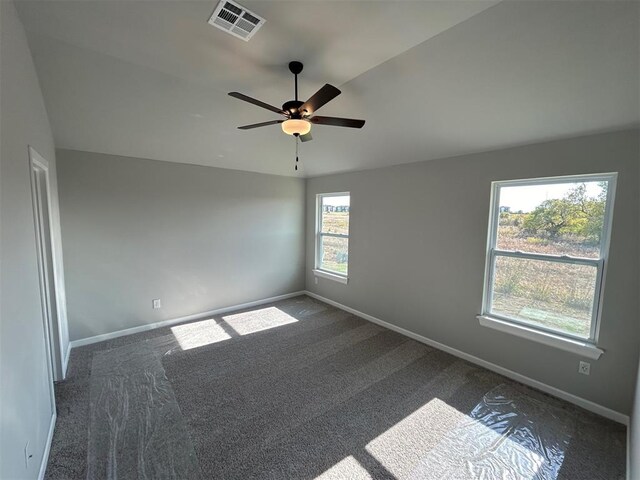 unfurnished room with dark carpet and ceiling fan