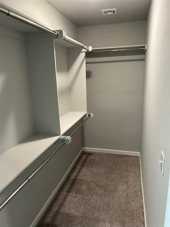 walk in closet featuring dark carpet