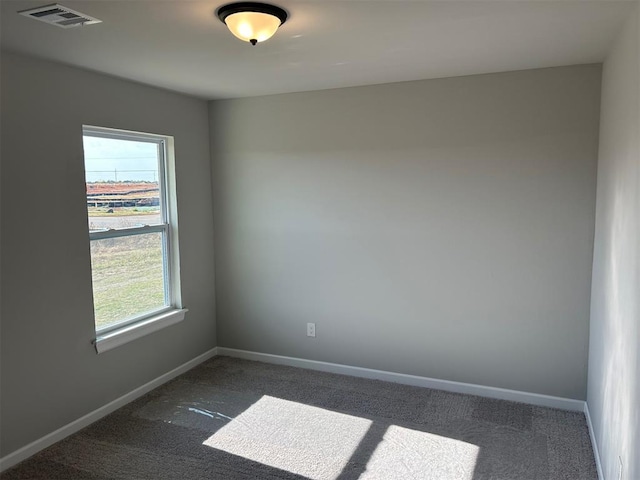 empty room featuring dark colored carpet and a wealth of natural light