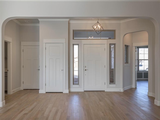 foyer featuring light hardwood / wood-style flooring, ornamental molding, and a notable chandelier