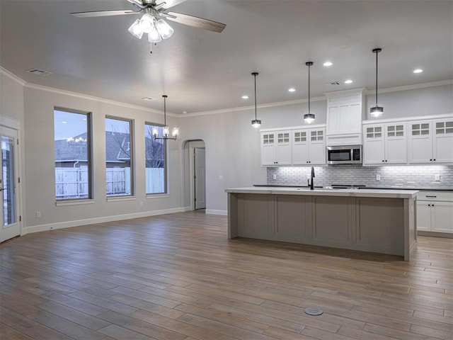 kitchen with white cabinets, ceiling fan, pendant lighting, and a center island with sink