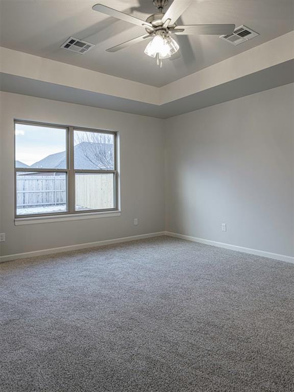 unfurnished room with a raised ceiling, carpet floors, a mountain view, and ceiling fan