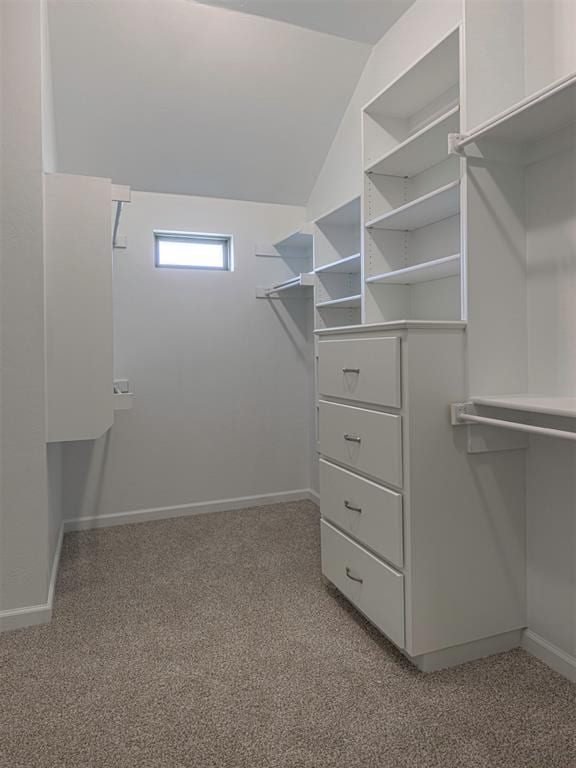 walk in closet with light carpet and vaulted ceiling