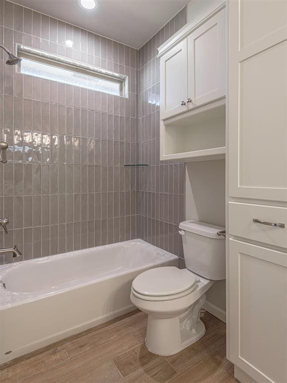 bathroom with hardwood / wood-style floors, toilet, and tiled shower / bath