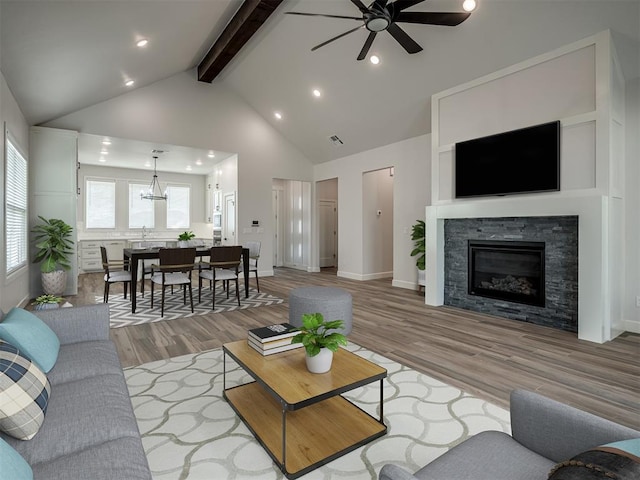 living room featuring beam ceiling, high vaulted ceiling, a fireplace, and light hardwood / wood-style flooring