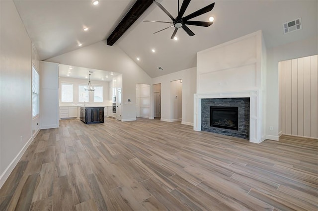 unfurnished living room with high vaulted ceiling, a fireplace, ceiling fan, beam ceiling, and light hardwood / wood-style flooring