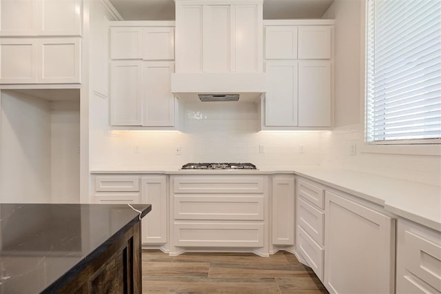 kitchen with white cabinetry, stainless steel gas stovetop, hardwood / wood-style flooring, and exhaust hood