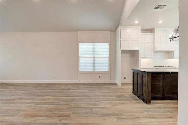 kitchen featuring cooktop, light hardwood / wood-style flooring, dark brown cabinets, decorative backsplash, and white cabinets