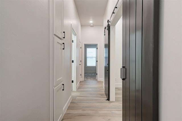 corridor featuring a barn door and light hardwood / wood-style flooring