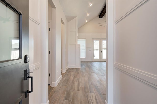 corridor featuring lofted ceiling with beams, light wood-type flooring, and french doors