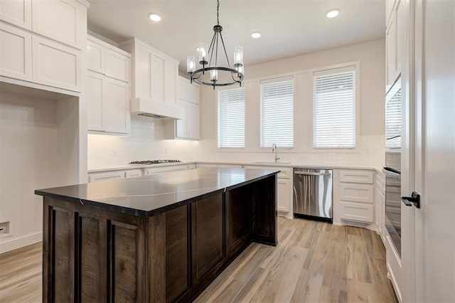 kitchen with pendant lighting, sink, white cabinets, a center island, and stainless steel dishwasher