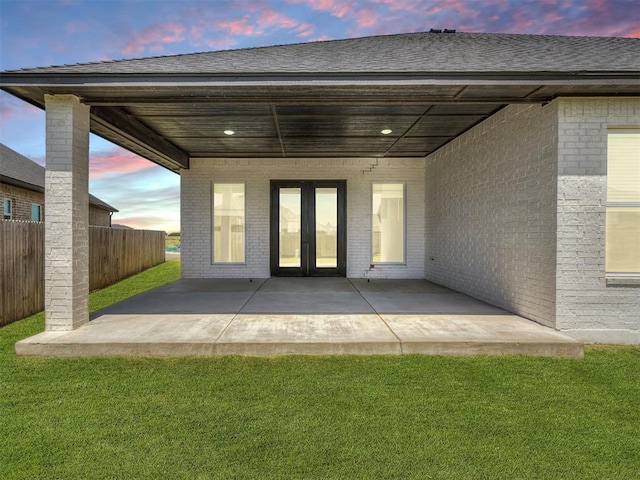 back house at dusk with a yard and a patio area