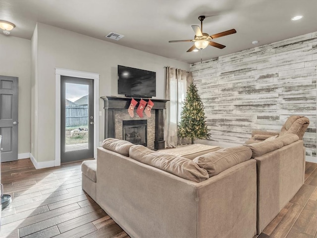 living room featuring a stone fireplace, ceiling fan, and hardwood / wood-style flooring