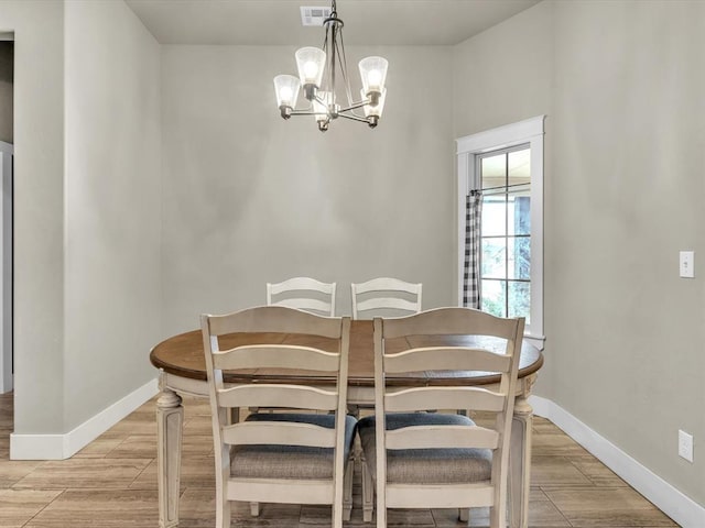 dining space with light wood-type flooring and an inviting chandelier