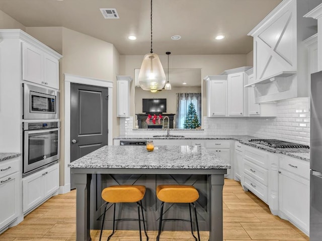 kitchen with white cabinets, a kitchen island, a kitchen bar, and stainless steel appliances