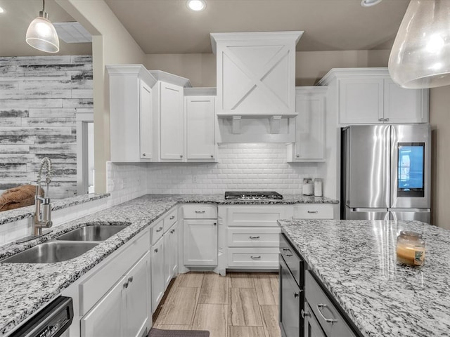 kitchen with appliances with stainless steel finishes, white cabinetry, hanging light fixtures, and sink