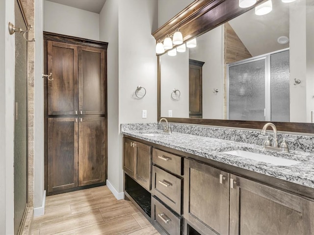 bathroom with vanity, a shower with shower door, lofted ceiling, and hardwood / wood-style flooring