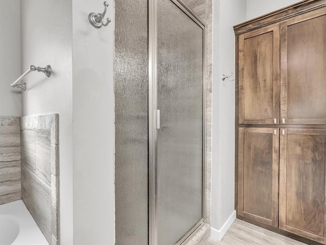 bathroom with hardwood / wood-style flooring and an enclosed shower