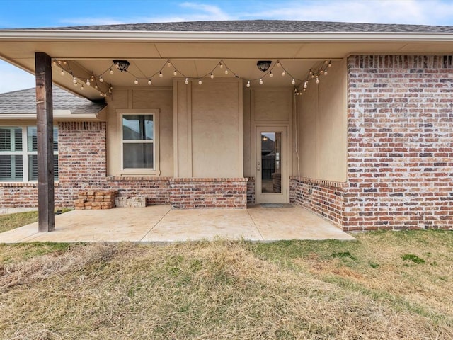 view of exterior entry with a lawn and a patio