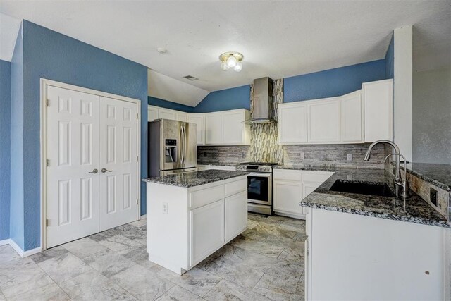 kitchen with stainless steel appliances, sink, white cabinetry, a center island, and wall chimney range hood