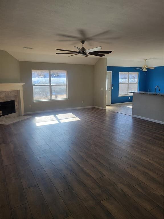 unfurnished living room with a high end fireplace, ceiling fan, dark hardwood / wood-style flooring, and sink