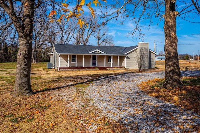 single story home featuring covered porch, central air condition unit, and a front yard