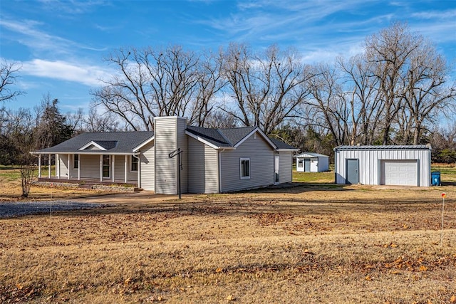 view of side of home with a porch, a yard, a garage, and an outdoor structure