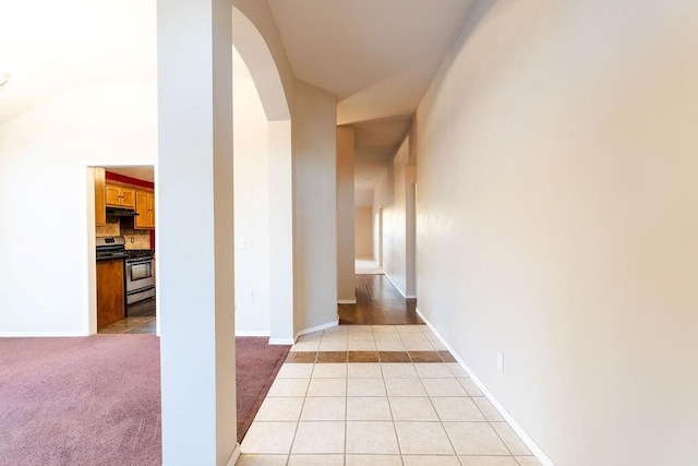 corridor with light colored carpet and lofted ceiling