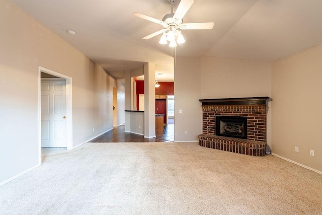 unfurnished living room featuring a brick fireplace, dark carpet, and ceiling fan