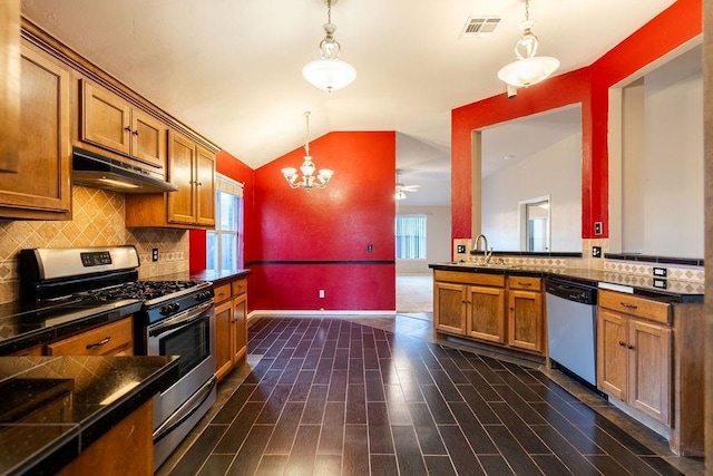 kitchen featuring dark wood-type flooring, kitchen peninsula, pendant lighting, vaulted ceiling, and appliances with stainless steel finishes